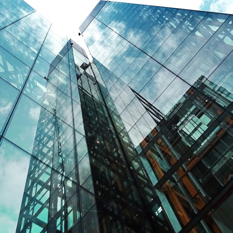 A striking view of a modern glass skyscraper reflecting the sky and clouds.